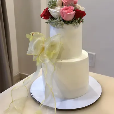 A two-tiered cake inspired by the elegance of Bridgerton. The bottom tier is Salted Caramel & Almond, and the top is Mango & White Chocolate, all enrobed in smooth vanilla buttercream.