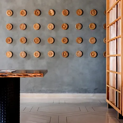 A detail from the Anthea Pharma project, showing the eye-catching hexagonal terrazzo flooring with brass and aluminum inlays. The exposed concrete walls and carved wooden artwork create a rich textural contrast.