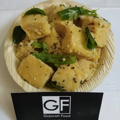 This is my soft and spongy Khaman, garnished with mustard seeds, curry leaves, and green chillies. It's a light and savory steamed snack that is a favorite for breakfast or tea time.