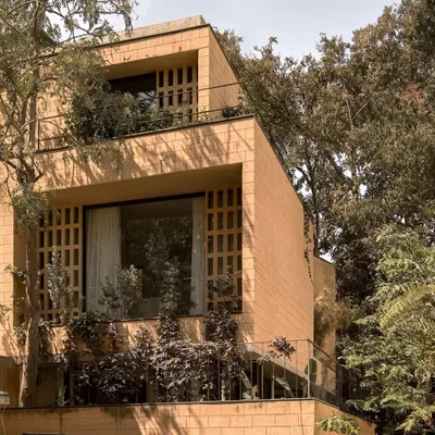 The Debris Block House in Bangalore is surrounded by trees, allowing for full-height windows and jaali screens. The stepping volumes are built with blocks made from debris from the original structure that once stood on this plot.