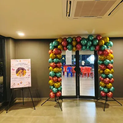 A colorful entrance arch made with red, gold, and teal chrome balloons makes a bold statement. Paired with a personalized welcome easel, it's the perfect way to greet guests and set a festive tone for the party.