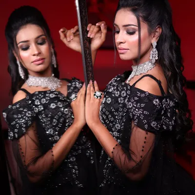 A dramatic mirror shot of a model in my black off-shoulder ball gown. The smoky makeup and sparkling diamond jewelry complete this glamorous look, perfect for a grand evening event.