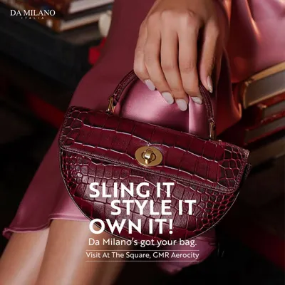 A close-up of a woman holding a chic, deep red handbag from Da Milano. This piece, with its croc texture and gold hardware, is perfect for slinging, styling, and owning your look.