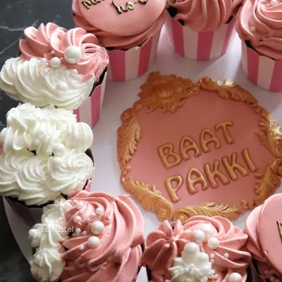 My "Baat Pakki" platter featuring a central cookie plaque and surrounded by pink and white frosted cupcakes with pearl details.