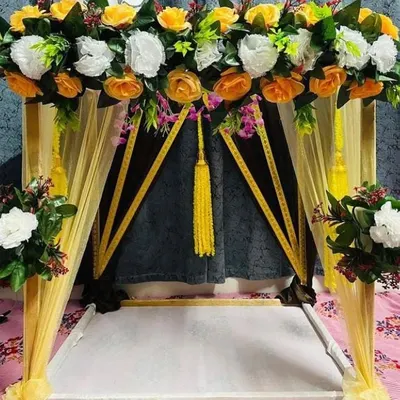 A close-up of a bright and sunny canopy decoration. This setup uses vibrant yellow and white artificial roses with yellow fabric drapes, creating a welcoming and auspicious space for Ganpati sthapana.