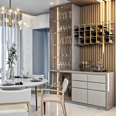This modern dining area features a custom bar unit we designed. It includes a tall, illuminated glass cabinet for stemware, handle-less drawers, and a wall-mounted gold wine rack against a fluted wood panel.