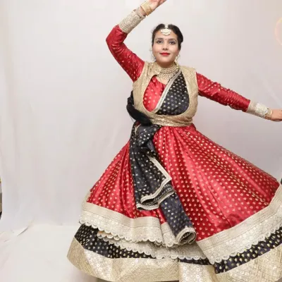 This custom red and black brocade anarkali is designed for a powerful Kathak performance. The outfit features a fitted jacket and a wide-flared skirt that accentuates the dancer's movements and stage presence.