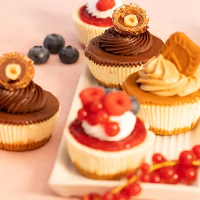 My egg-free baked baby cheesecakes are perfect for amping up your dessert table. This image shows a variety of toppings, including Nutella Rocher, Biscoff, and fresh berries.