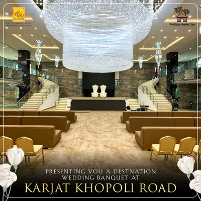 A full view of our majestic banquet hall in Karjat, designed for destination weddings. The central stage, flanked by grand staircases and crowned with a massive crystal chandelier, provides a breathtaking focal point for your special day.