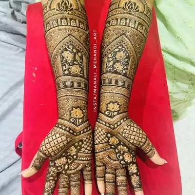 This full-arm design features classic palace-style arches and delicate lotus motifs. The intricate line work and symmetrical patterns create a look of pure elegance for the bride.