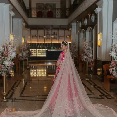A stunning portrait of the bride, her long, elegant veil spread out behind her in a grand hotel lobby. This shot is all about drama and elegance.
