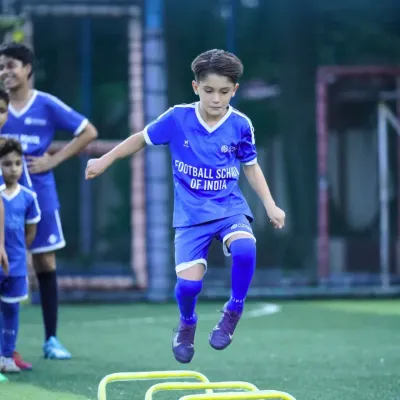 Agility and speed are crucial on the field. Here, a young athlete performs hurdle jumps, a key exercise in our training regimen designed to improve footwork, coordination, and explosive power for youth football players.