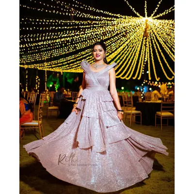 For the modern bride, a glamorous reception look. This custom-designed, shimmering rose gold gown features sculpted shoulders and a tiered, flowing skirt, perfect for a cocktail party or evening celebration.
