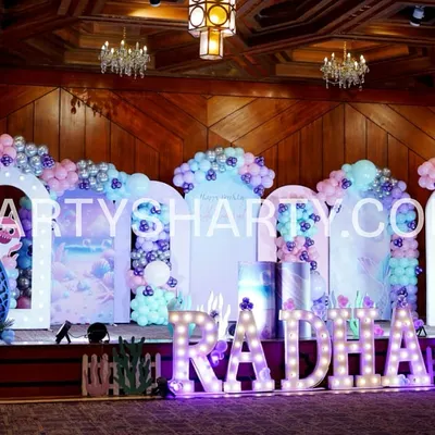 A stunning mermaid-themed stage with illuminated arches, underwater backdrops, and large marquee letters spelling out the birthday girl's name.