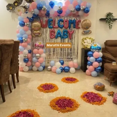 A complete decoration package for a baby welcome party. The setup includes a "Welcome Baby" balloon arch, a shimmery backdrop, and beautiful flower rangolis on the floor for a perfect blend of modern and traditional.