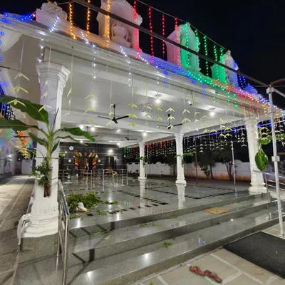 A wide view of the Vasavi Matha Temple decorated for a festival, with colorful lights, banana plantains, and hanging leaf decorations.