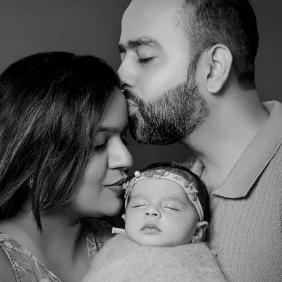 A tender black and white portrait of new parents embracing their sleeping baby. This style emphasizes the raw emotion and love in the moment.