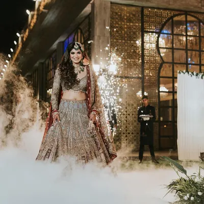 A grand bridal entry. The makeup is designed to be dramatic and visible, ensuring the bride is the center of attention in this smokey, cinematic shot.