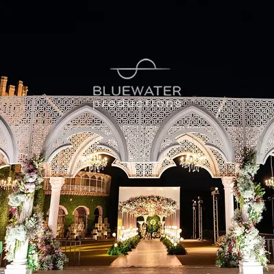 A wide-angle view of our 'Blue Palace' reception stage, showcasing the grand scale of the custom-fabricated white arches against the historic Bangalore Palace venue.