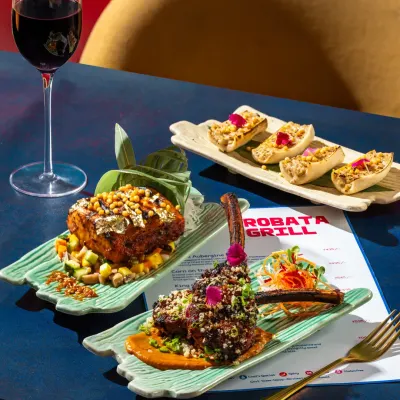 A vibrant spread of Japanese robata grill items, including lamb chops and paneer skewers, styled with a glass of red wine for a modern dining experience.