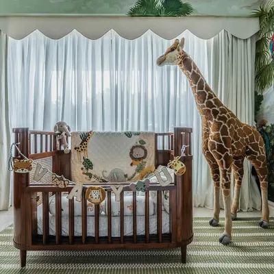 The centerpiece of Vayu's nursery. This classic wooden crib, with its beautiful detailing, stands against a hand-painted jungle mural. The life-sized giraffe adds a touch of pure magic to the room.
