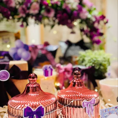 A close-up of the decorative elements in our 'Home in Hues' hamper. The shimmering rose-gold jars and fresh purple flowers add a touch of magic and elegance to a new living space.