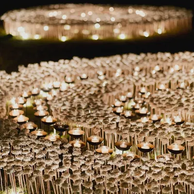 We created an illusion, not just a venue. This artistic installation features a field of individual white flowers and glowing candles, designed to evoke a sense of wonder and create an ethereal, dreamlike atmosphere.