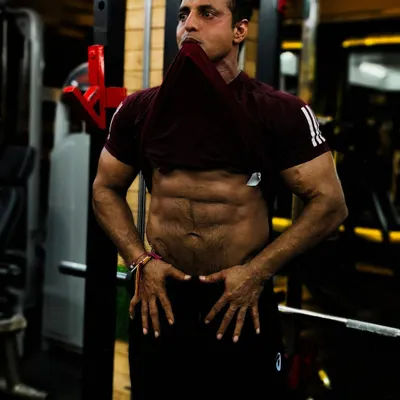 The result of discipline. This client is showing off his well-defined abs after a workout. A lean physique like this is achieved with a combination of a strict diet plan and consistent ab exercises.