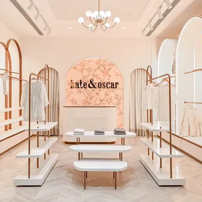 A full view of the Kate & Oscar retail space. The symmetrical design, with its repeating arches and central display tables, creates a clear and calming path for customers to navigate the store.