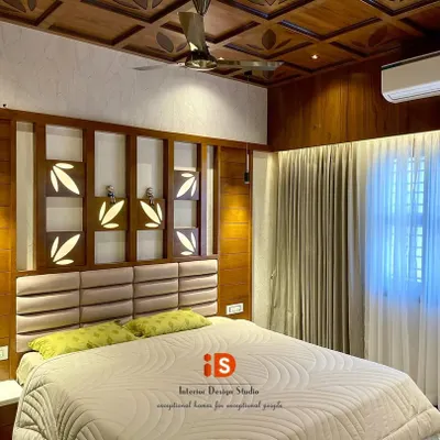 This traditional master bedroom is a showcase of exquisite woodwork. It features a custom-designed headboard with backlit leaf motifs and a stunning coffered ceiling made from polished wood, creating a warm and luxurious ambiance.