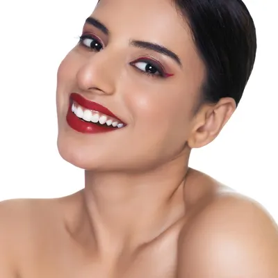 A clean, bright headshot perfect for an actor's portfolio. The focus is on the model's warm smile and the striking red winged eyeliner, showing off personality and makeup artistry.