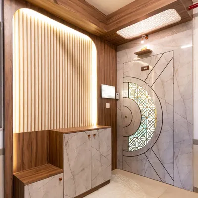 This grand entryway makes a statement with a marble-finish door featuring a geometric pattern, paired with a fluted wood panel wall and integrated seating and storage.