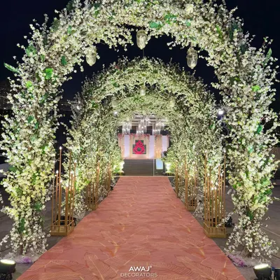A fairytale entrance tunnel made of white cherry blossom branches, creating a magical, starlit path for guests to walk through.