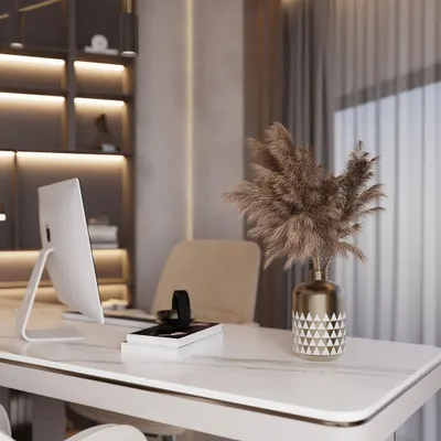 A detail shot of a luxury home office desk. The white marble-finish tabletop is complemented by a decorative vase with pampas grass and a backdrop of custom, backlit shelving, creating a workspace that is both stylish and serene.