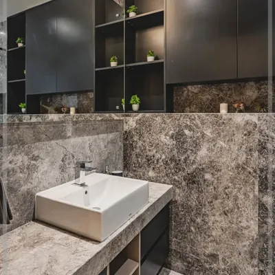 This monochromatic bathroom is all about opulence. The dark vanity and storage units, set against a dramatic grey marble, create a space that is minimalist yet lavish, showing a deep connection with high-end design.