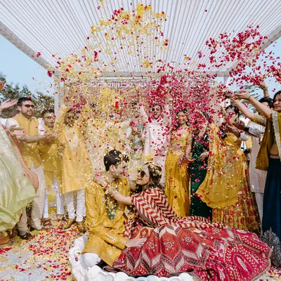 A perfect explosion of color and joy. This shot of Tanika and Naman being showered with flower petals during their haldi ceremony in Jaipur captures the essence of a happy, chaotic celebration.