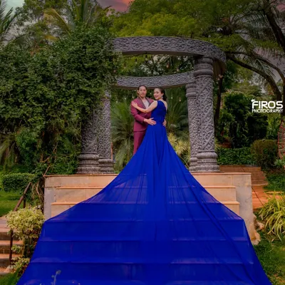A stunning sunset shot with a dramatic flowing gown. The vibrant colors of the sky and the dress create a powerful, cinematic pre-wedding portrait.