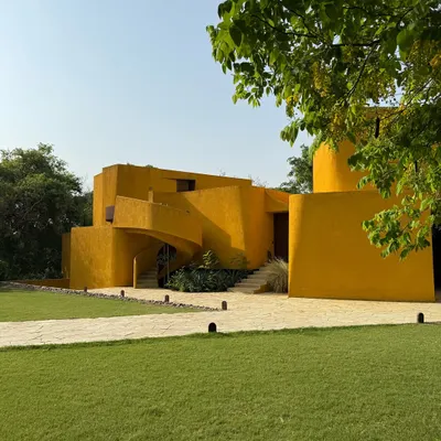 The main structure of Anvaya, viewed from the lawn, showcases the interplay of sharp lines and soft curves against a clear blue sky, a core tenet of our design philosophy.