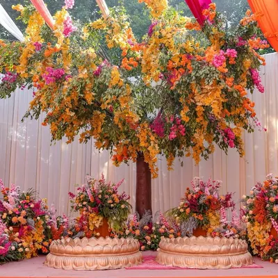 For this Haldi, I designed a magnificent 'tree of life' as the centerpiece, blooming with vibrant orange and pink flowers, creating a stunning and meaningful backdrop for the couple.
