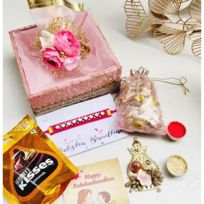 A complete Rakshabandhan gift set in a beautiful pink brocade box. This hamper includes a rakhi, a greeting card, Hershey's Kisses, a potli of dry fruits, and traditional roli-chawal for the ceremony.