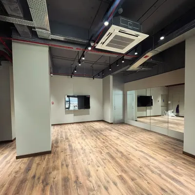 This wide angle shows the full expanse of the studio. You can see how the mirrors on the wall create a great sense of depth, making the space feel even larger and more dynamic. It's an ideal setup for large group activities or workshops.
