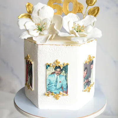 Celebrating 60 years in style with this elegant hexagonal cake. It features edible photos in gold frames and is topped with beautiful, handmade white sugar flowers and a gold "60" topper.