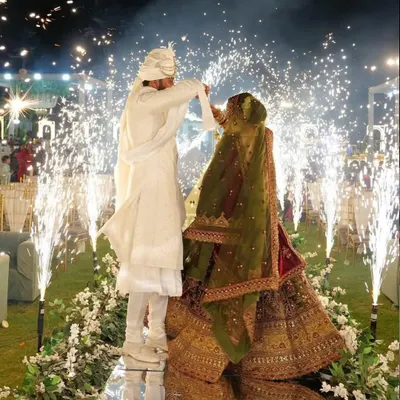 A stunning Varmala moment on a raised mirror stage. The couple is surrounded by an arc of cold pyro fountains, with their reflection creating a beautiful and complete picture.