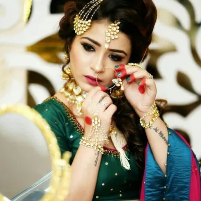 A close-up shot of a model getting ready, showcasing intricate hair jewelry, a nath, and haath phool. You can rent these pieces to achieve a complete, polished look.