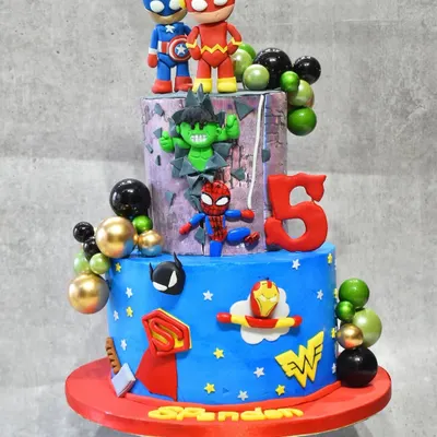 A superhero spectacular for a 5th birthday. This three-tier cake brings together the Avengers and DC heroes with edible figurines of Captain America, Flash, Hulk, Spider-Man, and more, all made with a delicious chocolate hazelnut flavor inside.