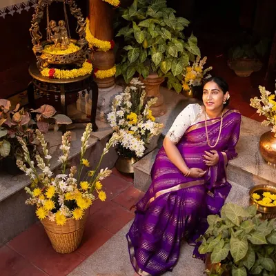 A beautiful portrait of an expecting mother in a traditional setting, surrounded by flowers and brass decor, capturing the essence of her maternity journey.