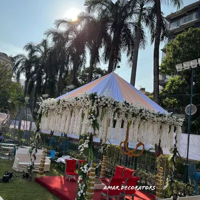 A beautiful shot of a sunset wedding ceremony I designed. The mandap is draped in white fabric with hanging floral strings, creating a serene and heavenly space for the couple to take their vows as the sun goes down.