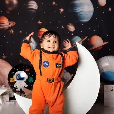 A joyful little astronaut celebrating his first birthday, standing proudly on the moon in our outer space set.
