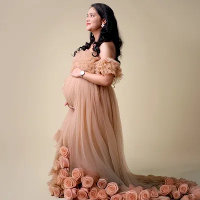 This unique maternity gown features a trail of delicate fabric roses, creating a stunning and romantic effect. It's one of the many designer options available in our studio wardrobe.