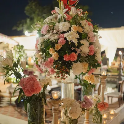 A lush and romantic floral centerpiece, combining roses, lilies, and chrysanthemums in shades of pink and white. I use abundant, high-quality florals to create a feeling of opulence and luxury.